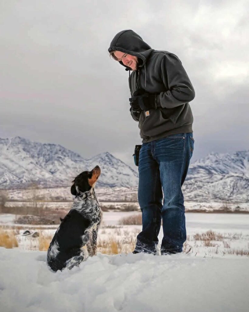 Dog focused on a trainer in a snowy mountain setting